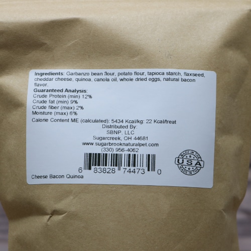 Nutritional label on a pack of Sugar Brook's Cheese Bacon Quinoa dog treats showing ingredients and guaranteed analysis on a kraft paper background