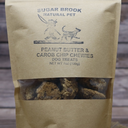 Close-up of the Sugar Brook Natural Pet Peanut Butter & Carob Chip Chewies Dog Treats in a kraft bag, with a glimpse of the treats visible through the packaging window.