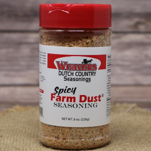 Close-up of Weaver's Spicy Farm Dust Seasoning bottle, featuring a red cap and label, on a textured burlap surface.