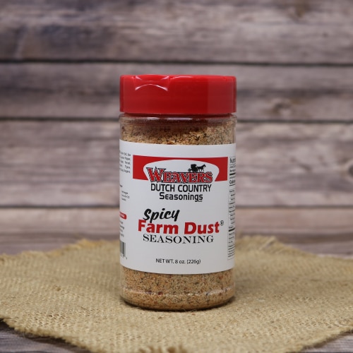 A bottle of Weaver's Dutch Country Seasonings Spicy Farm Dust Seasoning with a red cap, placed on a burlap mat and wooden background.