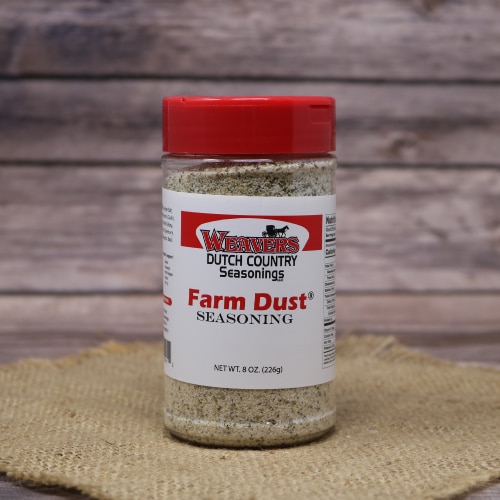Jar of Weaver's Dutch Country Seasonings Farm Dust with a red lid, positioned on a burlap surface against a wooden backdrop.