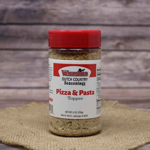 A jar of Weaver’s Dutch Country Seasonings Pizza & Pasta Topper with a red cap, set against a hessian backdrop and wooden table.