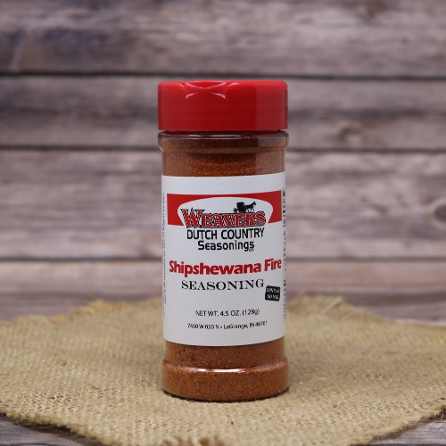 Bottle of Weaver’s Dutch Country Seasonings Shipshewana Fire Seasoning with a red cap, displayed on a burlap mat and wooden background.