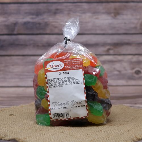 Clear plastic Ashery bag with red and white sticker label filled with multi-colored candies, sitting on a burlap material with wood background