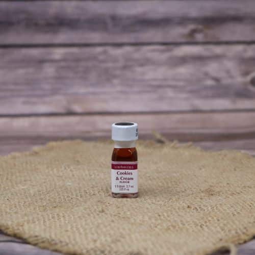 small clear bottle with a red and white label and a sealed lid, with a red liquid in it, sitting on a burlap material with wood background