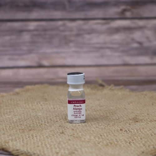 small clear bottle with a red and white label and a sealed lid, with a clear liquid in it, sitting on a burlap material with wood background
