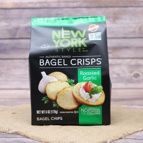 Black plastic bag with green accents and a picture of New York style bagel crisps, sitting on a burlap material with wood background
