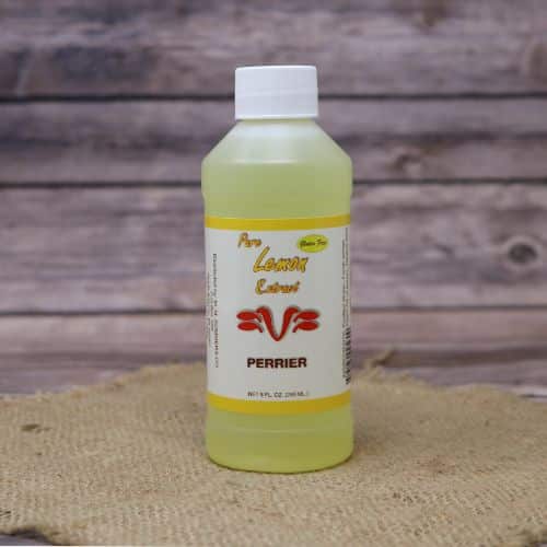 Small 8oz plastic bottle of yellow liquid with a white and green sticker label, sitting on a burlap material with wood background