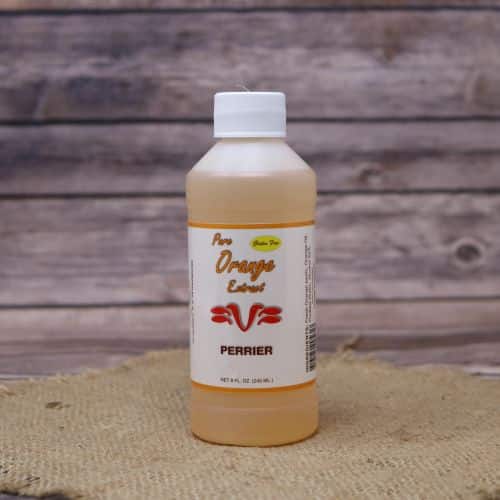 Small 8oz plastic bottle of orange liquid with a white and green sticker label, sitting on a burlap material with wood background