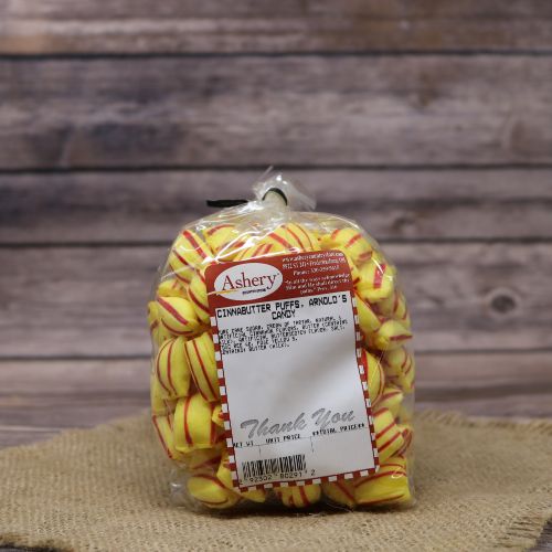 Clear plastic Ashery bag with red and white sticker label filled with yellow and red striped candies, sitting on a burlap material with wood background