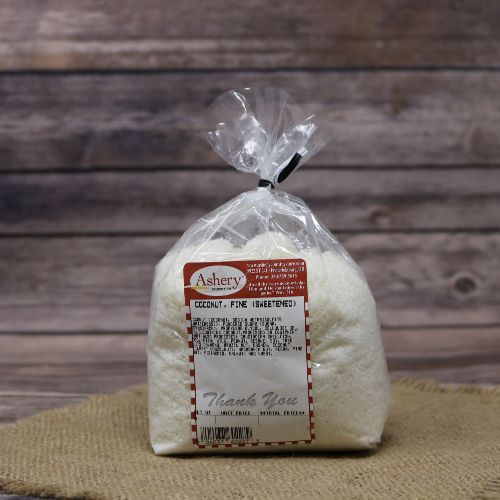 Clear plastic Ashery bag with red and white sticker label filled with shredded coconut, sitting on a burlap material with wood background