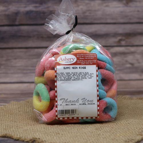 Clear plastic Ashery bag with red and white sticker label filled with colorful candies sitting on a burlap material with wood background