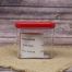 Clear plastic container with red lid that has a piece of paper with a list of ingredients, sitting on a burlap material with a wood background