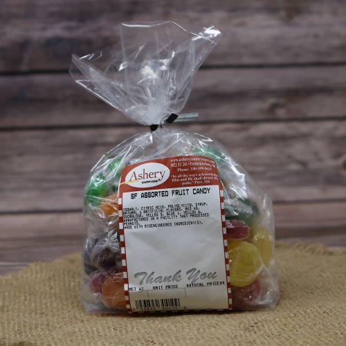 Clear plastic Ashery bag with red and white sticker label filled with multicolored candies, sitting on a burlap material with wood background