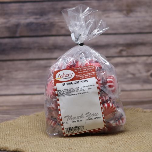 Clear plastic Ashery bag with red and white sticker label filled with red and white striped candies, sitting on a burlap material with wood background