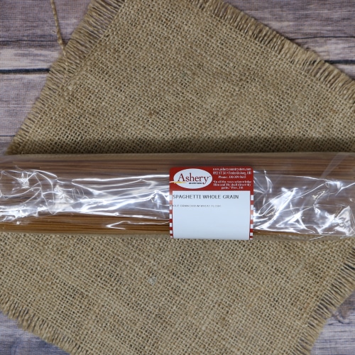 Long package of Asher's Whole Grain Spaghetti with a red and white label, over a rustic burlap cloth and wood background.