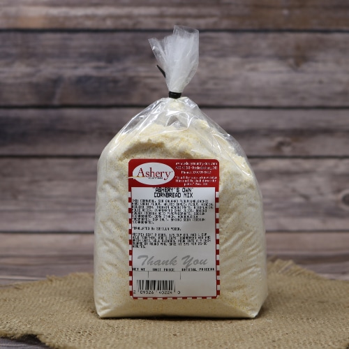 Bag of Ashery's Own Cornbread Mix on a burlap mat with a rustic wooden background.