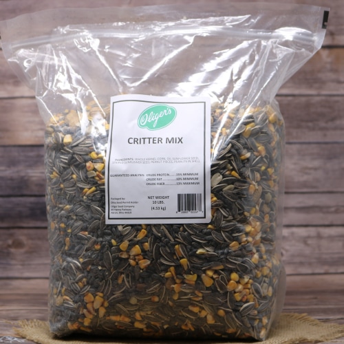 A large plastic bag of Asher's Critter Mix with a green and white label, filled with a blend of seeds and grains, on a wooden surface.