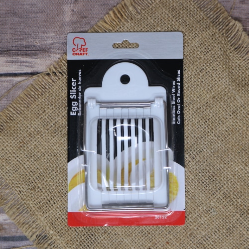 Chef Craft brand egg slicer in packaging, featuring a white base and stainless steel wires, displayed on a hessian background.