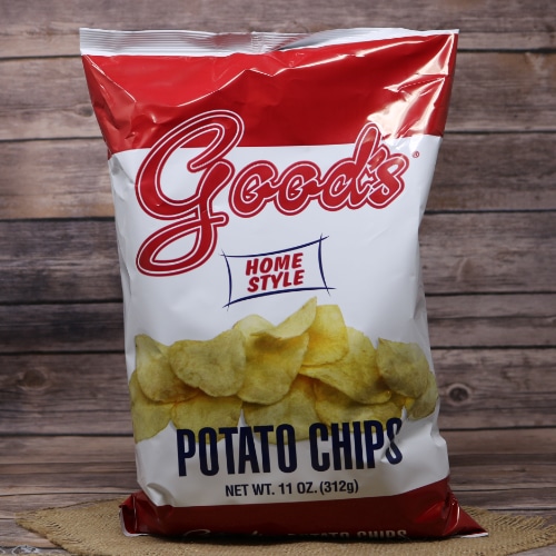 A bold red bag of Good's Home Style Potato Chips stands on a straw mat, with a wood-textured background highlighting the product.