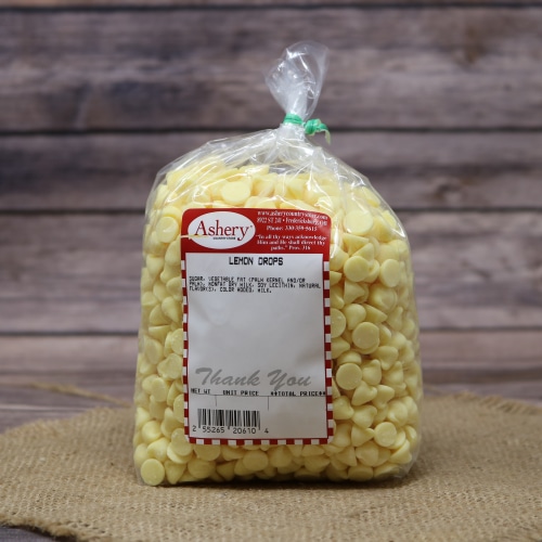 Bag of Ashery Lemon Drops for baking, a burst of yellow against the natural tones of the straw mat and wooden background.