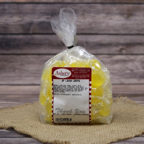 Bag of Ashery Sugar-Free Lemon Drops on a burlap mat with a rustic wooden background.